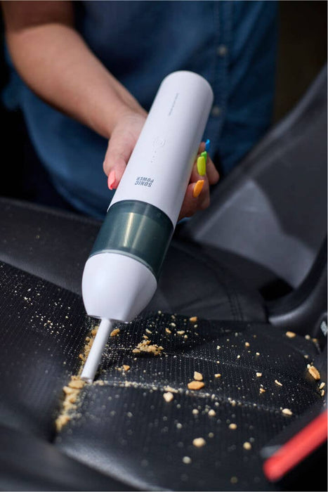 Person cleaning a car seat with a Sonic Power handheld vacuum cleaner.