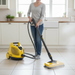 Person using a Vapamore steam cleaner on a tiled floor in a kitchen.