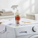 Stain-X pet stain and odor remover bottle on a washing machine with stains visible.
