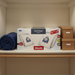 Miele AirClean GN Bags and filter on a shelf with a blue towel and brown boxes.