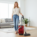 Woman holding a Miele C1 Centennial red vacuum cleaner in a living room. Capital Vacuum Raleigh Cary NC