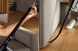Person using a Miele Duoflex HX1 Cordless Stick Broom Vacuum Cleaner Total Care, Black & Gold SQLL0 demonstrating crevice tool. Capital Vacuum Raleigh Cary NC