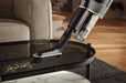 Person using a Miele Duoflex HX1 Cordless Stick Broom Vacuum Cleaner Total Care, Black & Gold SQLL0 Handheld vacuum cleaning a table in a living room setting. Capital Vacuum Raleigh Cary NC