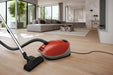 Red Miele vacuum cleaner on a wooden floor in a modern living room. Miele Guard M1 Terra Red SVWE0 Canister Vacuum Cleaner Capital Vacuum Raleigh Cary NC