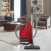 Red and gray Miele vacuum cleaner on a marble floor with a living room in the background. Miele Homecare C3 Canister Vacuum Cleaner SEB228 Capital Vacuum Raleigh Cary NC