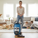 Woman using a Miele vacuum cleaner in a living room with children and a dog. Miele Turbo Team CX1 Bagless Canister Vacuum Cleaner SKCE0 Capital Vacuum Raleigh Cary NC
