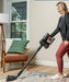Woman using a Riccar R65 cordless vacuum cleaner in a living room. Capital Vacuum Raleigh Cary NC