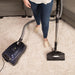 Person using a Riccar Prima vacuum cleaner on a carpeted floor. Riccar Prima canister vacuum cleaner with compact nozzle. Capital Vacuum Raleigh Cary NC