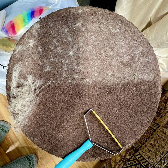 Round brown rug with a Uproot Clean Pro pet grooming tool on a wooden carpeted surface. Capital Vacuum Raleigh Cary NC