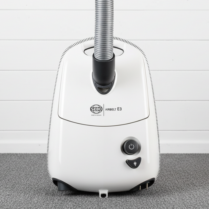 White Sebo E3 vacuum cleaner with a hose on a gray carpet against a white wall. Sebo Airbelt E3 Premium White Canister Vacuum 91646AM Capital Vacuum Raleigh Cary NC