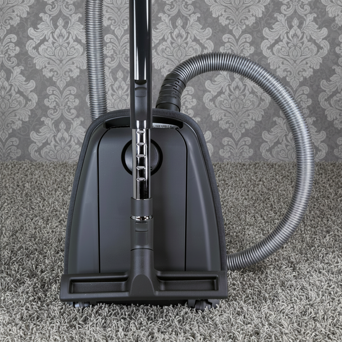 Vacuum cleaner on a carpet with patterned wallpaper in the background. Sebo Airbelt K3 Premium Blue Canister Vacuum 91698AM Capital Vacuum Raleigh Cary NC