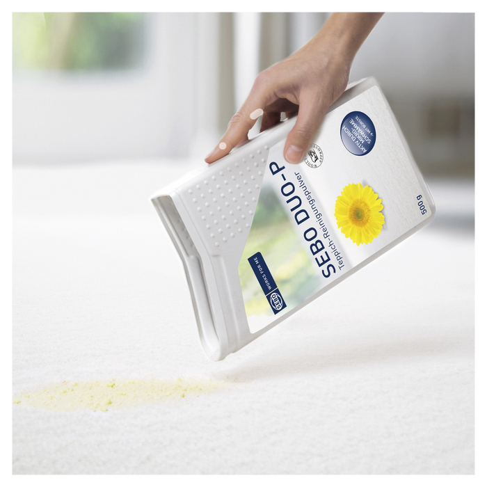 Hand holding a Sebo Duo-P product with a daisy on a white background. Sebo duo Carpet Cleaner 9401AM Capital Vacuum Raleigh Cary NC
