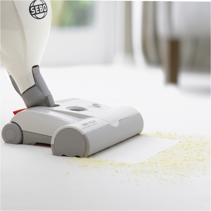 SEBO vacuum cleaner cleaning a white surface with scattered yellow particles. Sebo duo Carpet Cleaner 9401AM Capital Vacuum Raleigh Cary NC