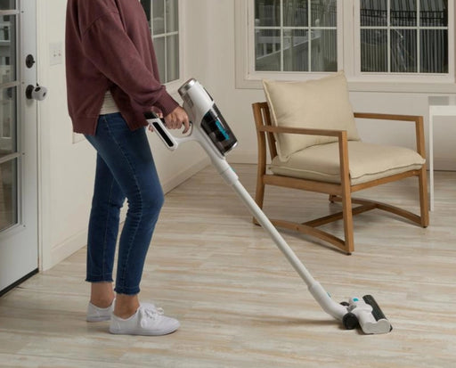 Woman using a Simplicity S67 cordless vacuum cleaner in a room. Capital Vacuum Raleigh Cary NC