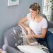Woman sitting on couch using Uproot Cleaner Pro on carpet. Capital Vacuum Raleigh Cary NC
