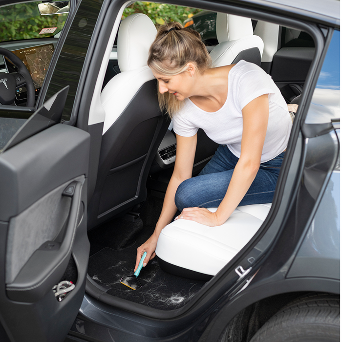 Woman using Uproot Cleaner Pro on automobile carpet under seat. Capital Vacuum Raleigh Cary NC